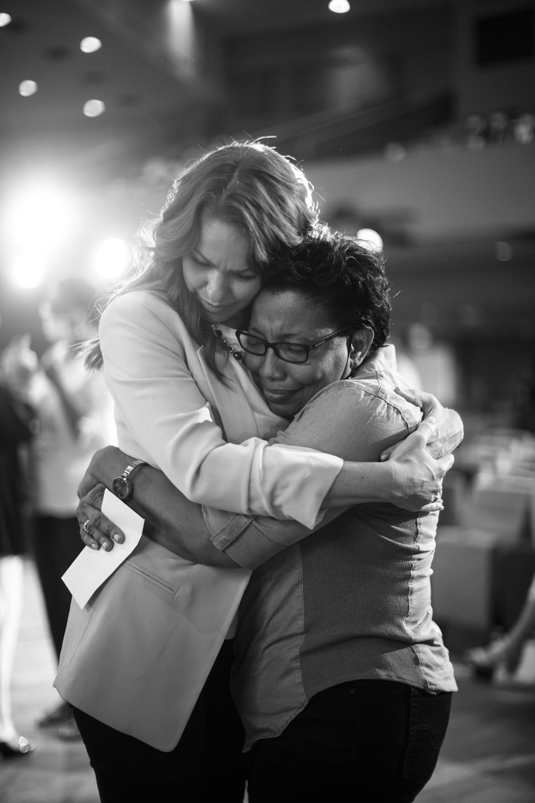 Two women embracing at the altar during a church service, black and white church photography