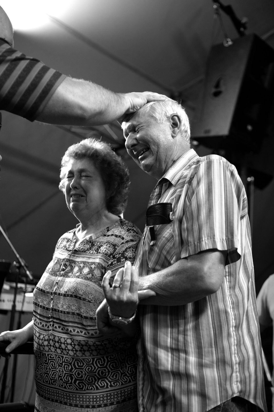 An older couple laughing with joy as they receive prayer in church