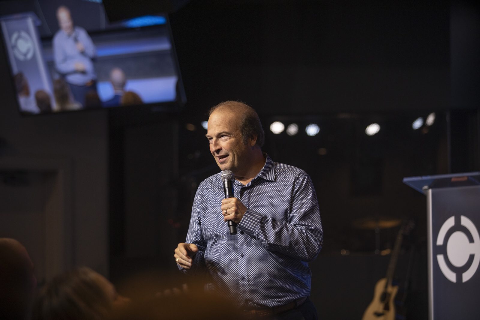 A preacher speaking from the stage during a church service