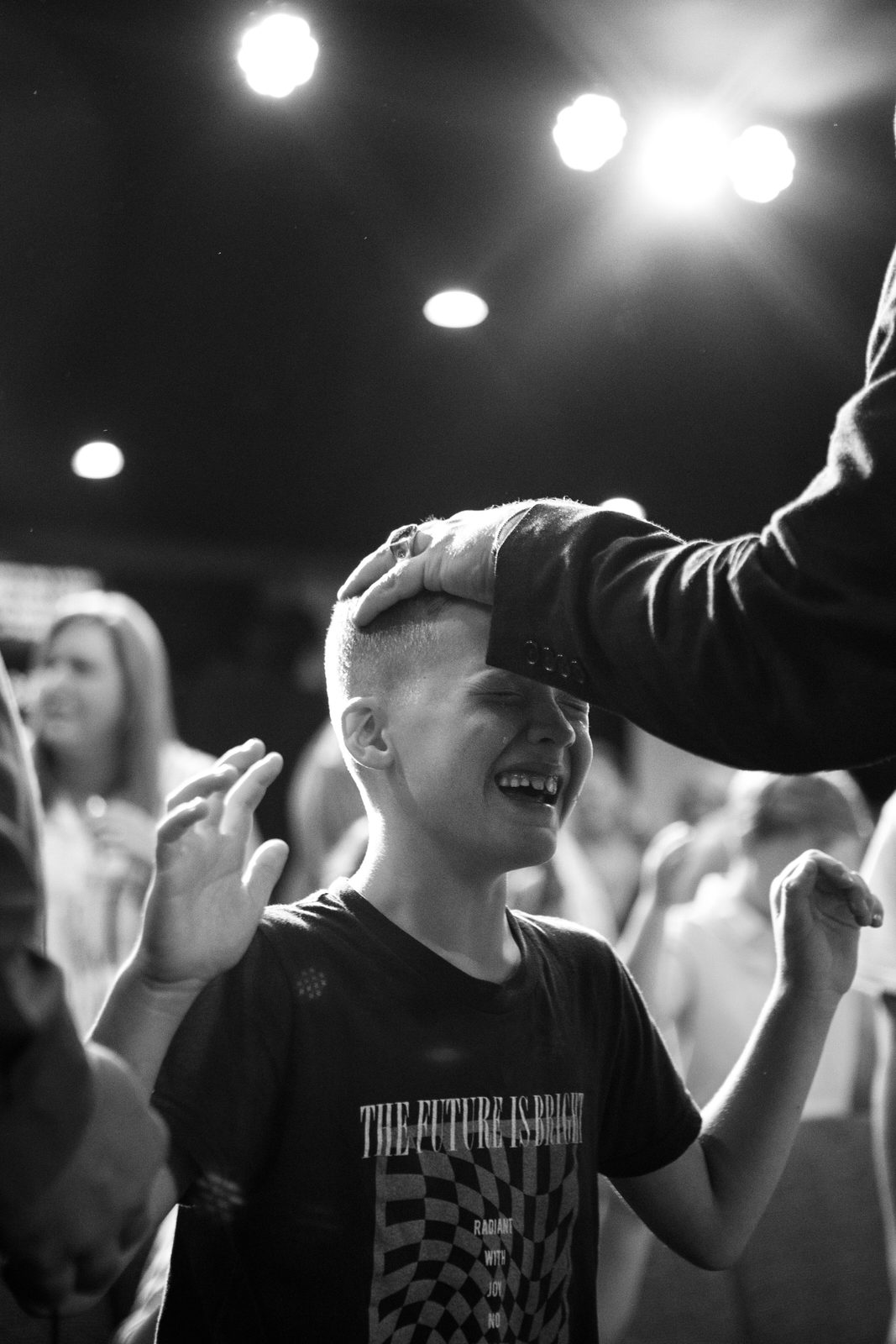 A young boy smiling as a minister lays hands on him at a revival service