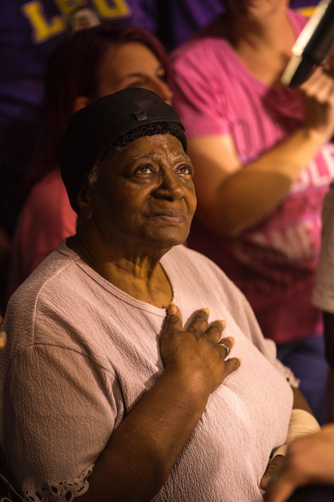 An older woman with her hand on her heart during worship at a revival meeting
