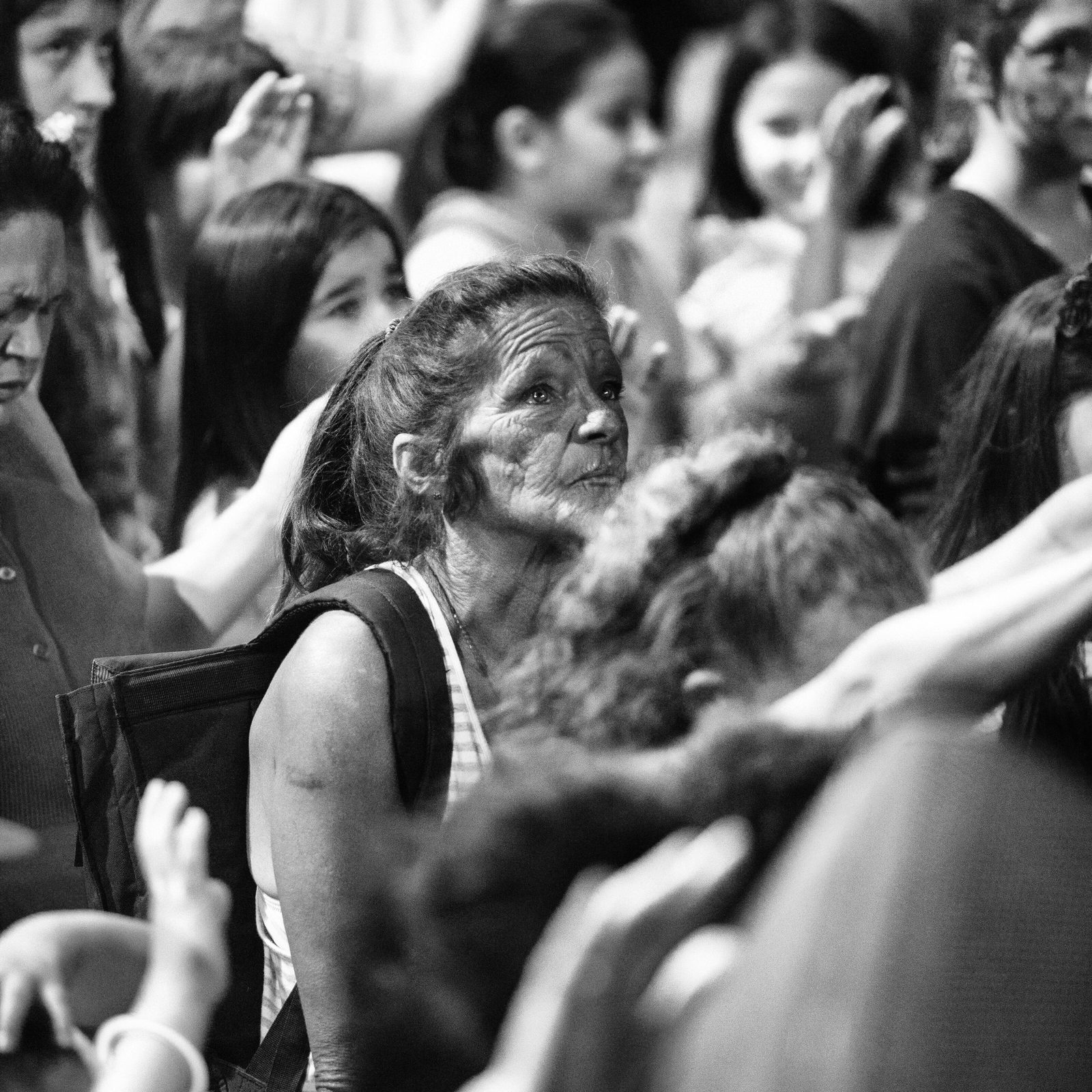 A woman with tears in her eyes worshipping in the crowd at a revival meeting